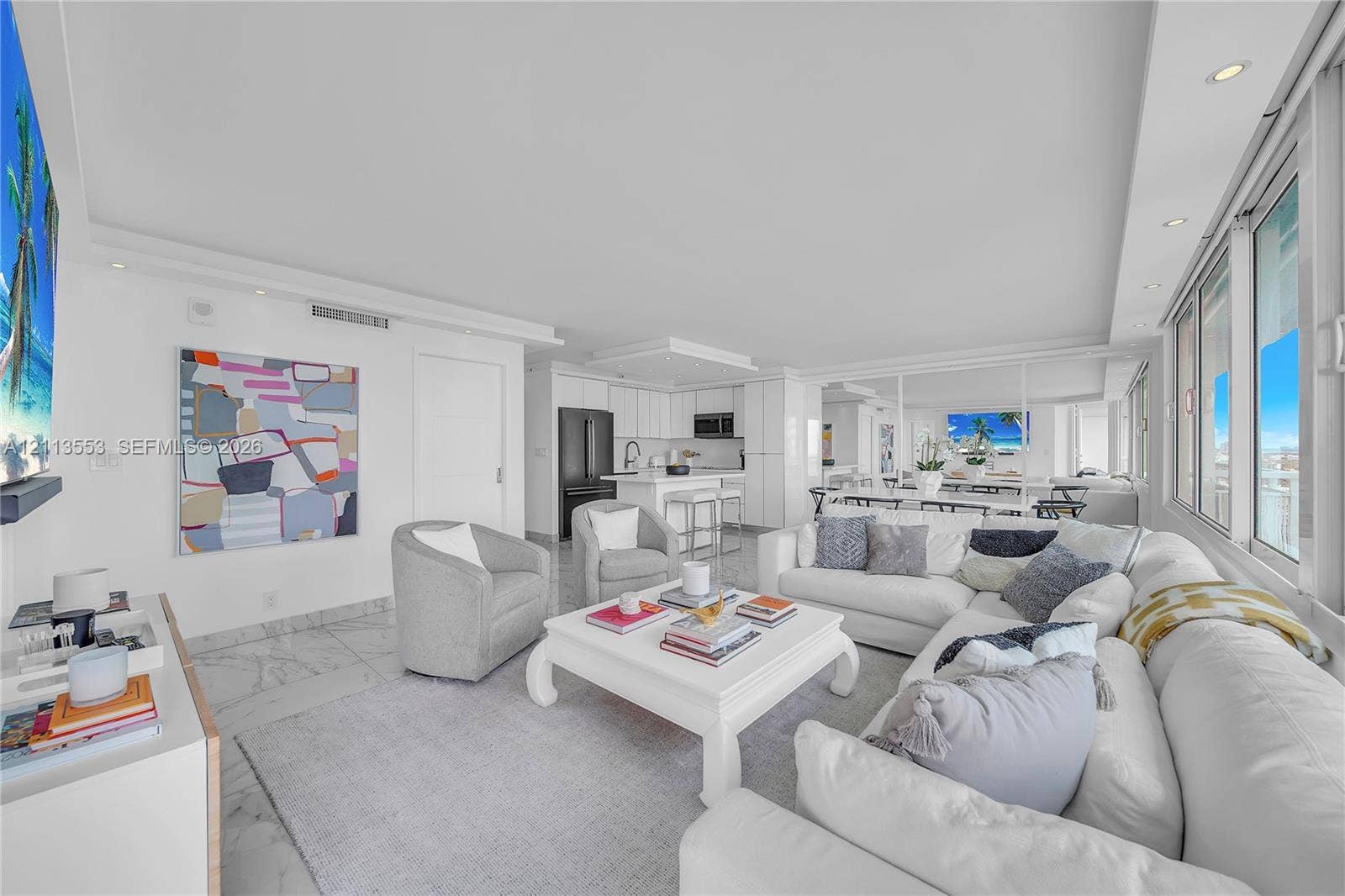 400 S Pointe Drive, #2106, Miami Beach, FL 33139 Open-concept interior featuring light-toned stone flooring, recessed ceiling lighting, a kitchen island with stone countertops, and floor-to-ceiling windows