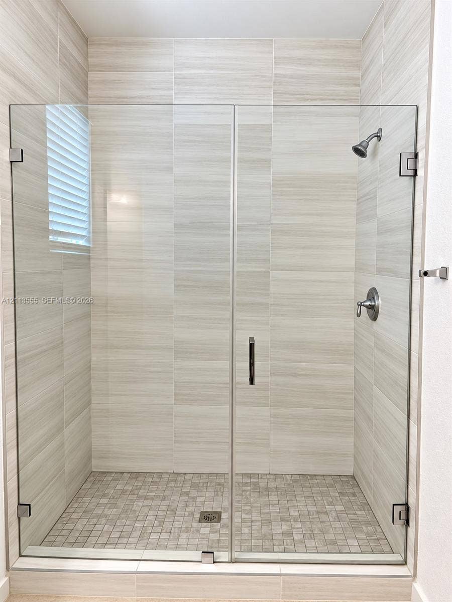 104 NW 31st Avenue, Fort Lauderdale, Fort Lauderdale, FL 33311 Walk-in shower featuring a frameless glass door, floor-to-ceiling large-format neutral tile, mosaic tile flooring, and wall-mounted metal fixtures