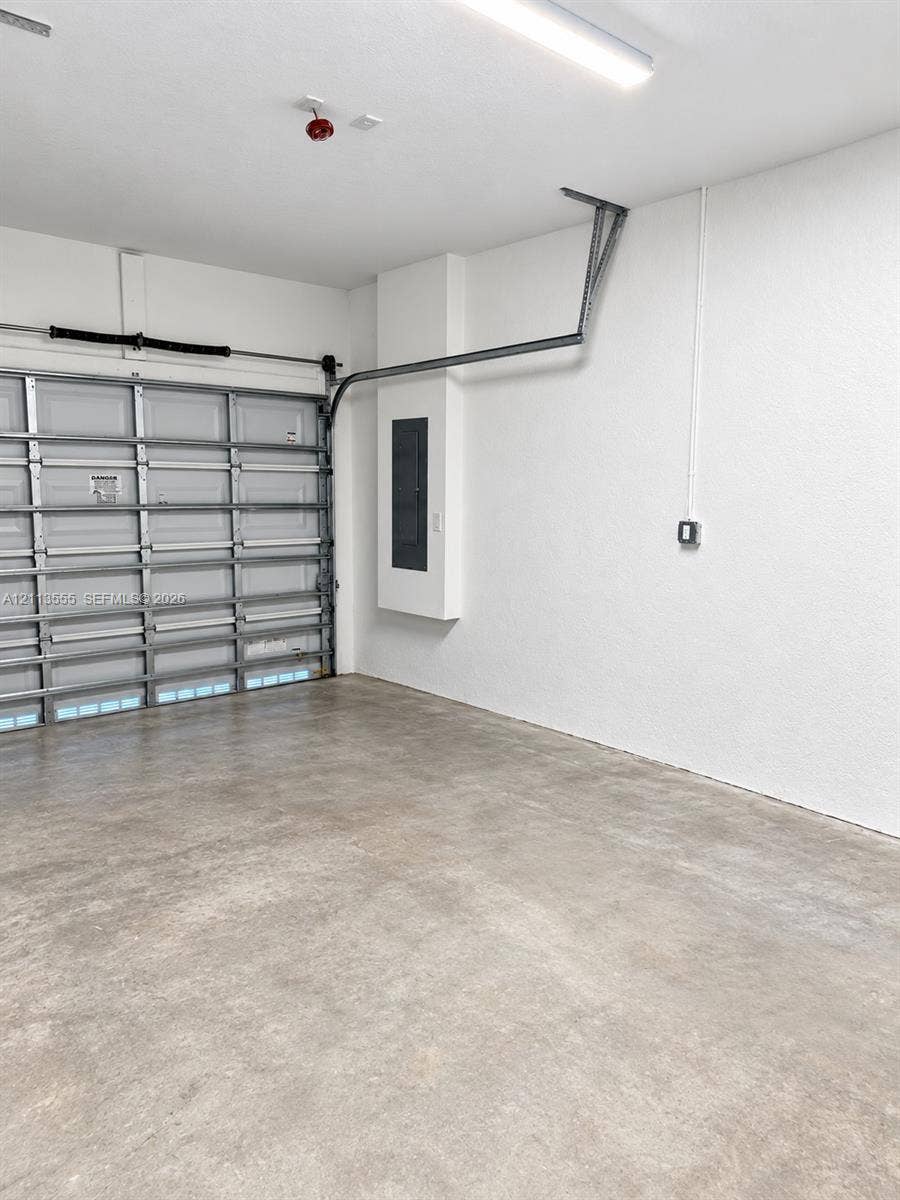 104 NW 31st Avenue, Fort Lauderdale, Fort Lauderdale, FL 33311 Garage interior featuring a concrete floor, sectional overhead door, linear LED lighting, and a recessed electrical service panel