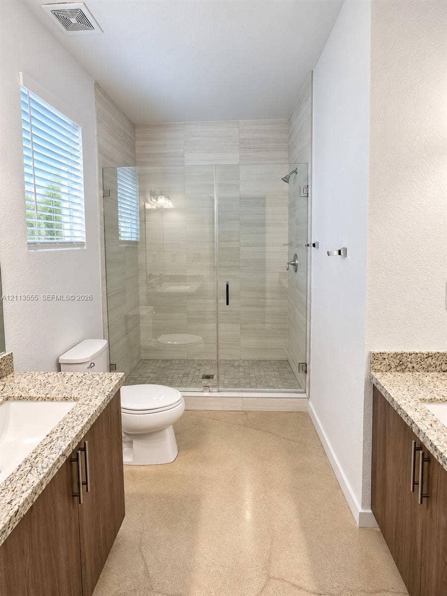 104 NW 31st Avenue, Fort Lauderdale, Fort Lauderdale, FL 33311 Dual wood-finish vanities with stone countertops, frameless glass shower enclosure, horizontal tile wall surround, and polished concrete flooring