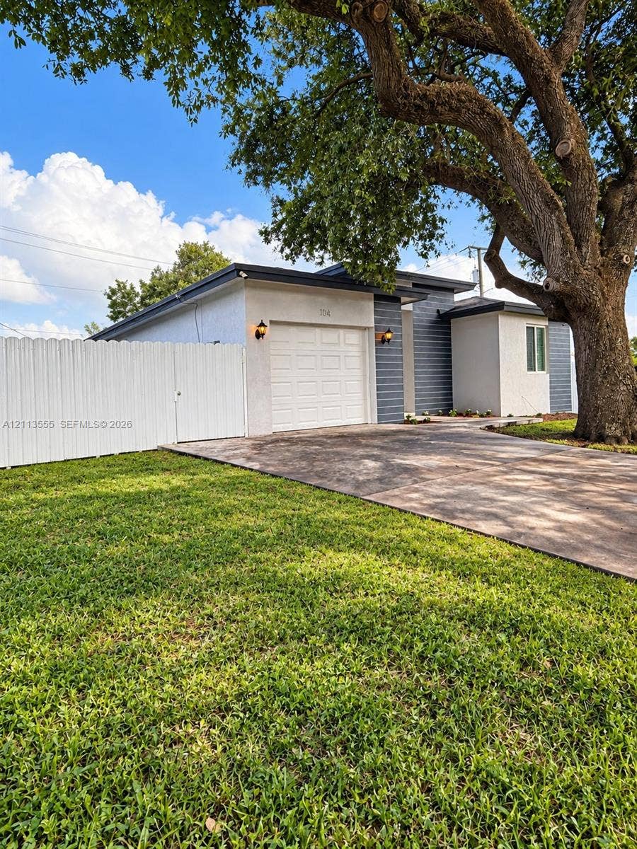 104 NW 31st Avenue, Fort Lauderdale, Fort Lauderdale, FL 33311 Single-story exterior featuring a stucco and horizontal siding facade, an attached garage, a concrete driveway, and a fenced perimeter