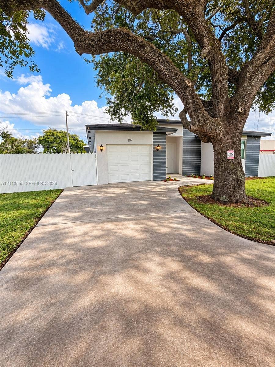104 NW 31st Avenue, Fort Lauderdale, Fort Lauderdale, FL 33311 Exterior facade featuring horizontal siding and a single-car garage, concrete driveway, and white privacy fencing