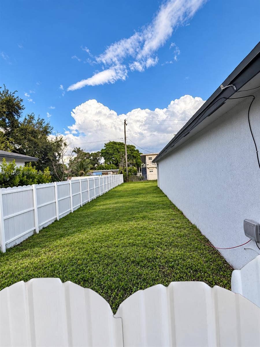 104 NW 31st Avenue, Fort Lauderdale, Fort Lauderdale, FL 33311 Side yard featuring a white vinyl privacy fence and a manicured lawn