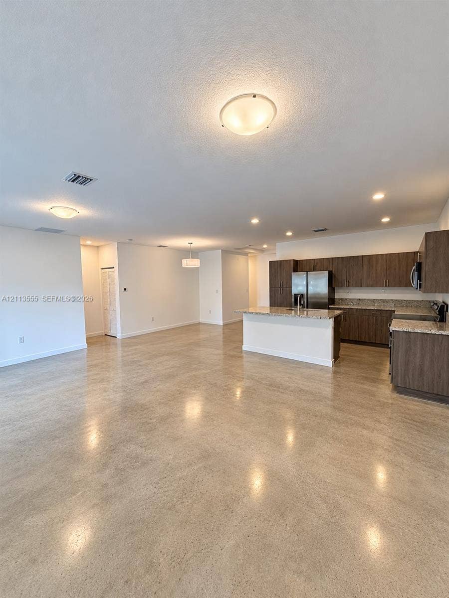 104 NW 31st Avenue, Fort Lauderdale, Fort Lauderdale, FL 33311 Open-concept interior featuring polished concrete flooring, kitchen with dark wood-finish cabinetry, stone-style countertops, an island, and flush-mount lighting fixtures