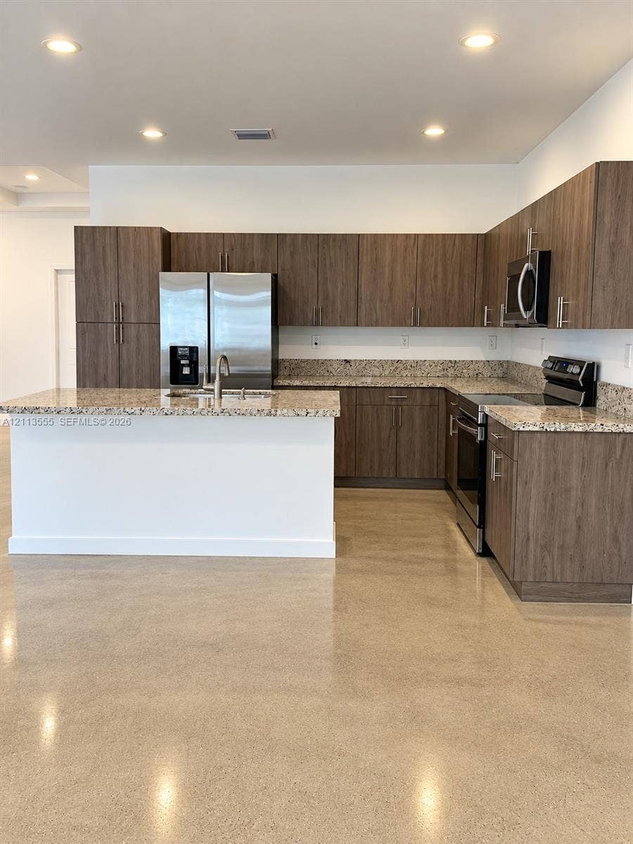 104 NW 31st Avenue, Fort Lauderdale, Fort Lauderdale, FL 33311 Kitchen featuring flat-panel wood-grain cabinetry, stone-finish countertops, stainless steel appliances, a center island with a double-basin sink, and polished concrete flooring