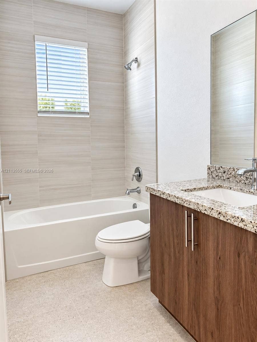 104 NW 31st Avenue, Fort Lauderdale, Fort Lauderdale, FL 33311 Bathroom featuring a tub-shower combination with horizontal tile surround, a wood-finish vanity with a stone-composite countertop, and a built-in recessed mirror