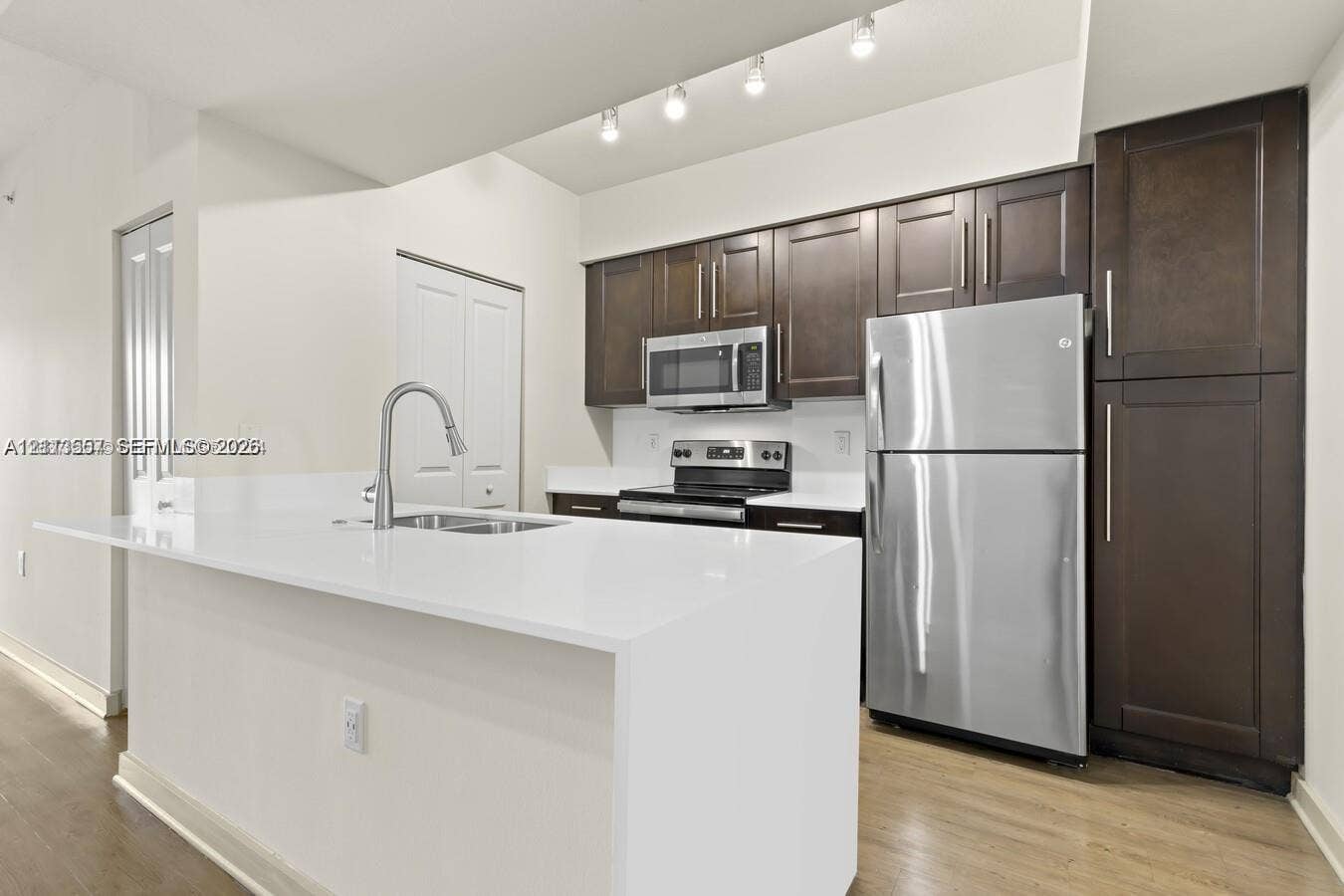 320 Franklin Club Drive, #Boca 1, Delray Beach, Delray Beach, FL 33483 Kitchen featuring dark wood-finish cabinetry, white solid-surface countertops, a stainless steel refrigerator, a built-in microwave, and recessed track lighting