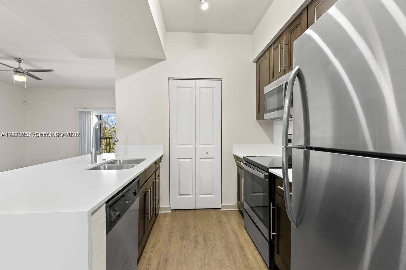 320 Franklin Club Drive, #Boca 1, Delray Beach, Delray Beach, FL 33483 Kitchen featuring dark wood-finish cabinetry, solid-surface countertops, stainless steel appliances, a double-basin undermount sink with a pull-down faucet, and wood-finish flooring