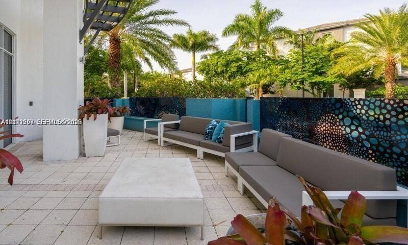 320 Franklin Club Drive, #Boca 1, Delray Beach, Delray Beach, FL 33483 Outdoor terrace featuring paved stone flooring, decorative privacy screening with patterned accents, and perimeter landscaping with mature palm trees
