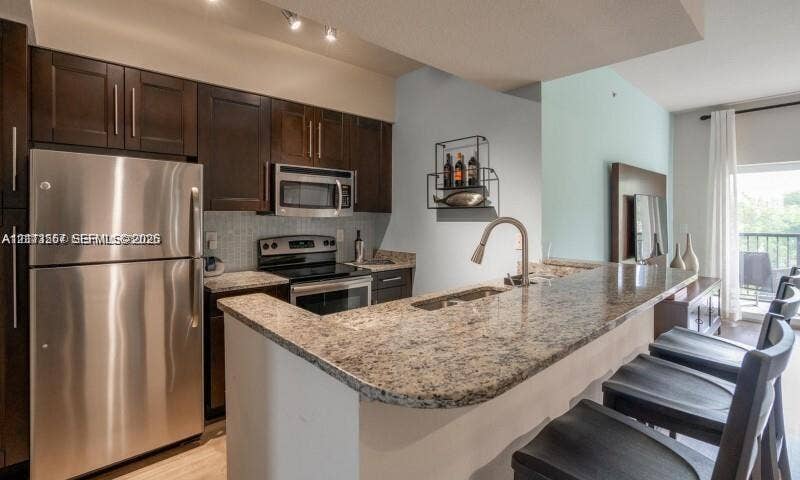 320 Franklin Club Drive, #Boca 1, Delray Beach, Delray Beach, FL 33483 Kitchen featuring dark wood cabinetry, stone countertops, stainless steel appliances, breakfast bar, and undermount sink
