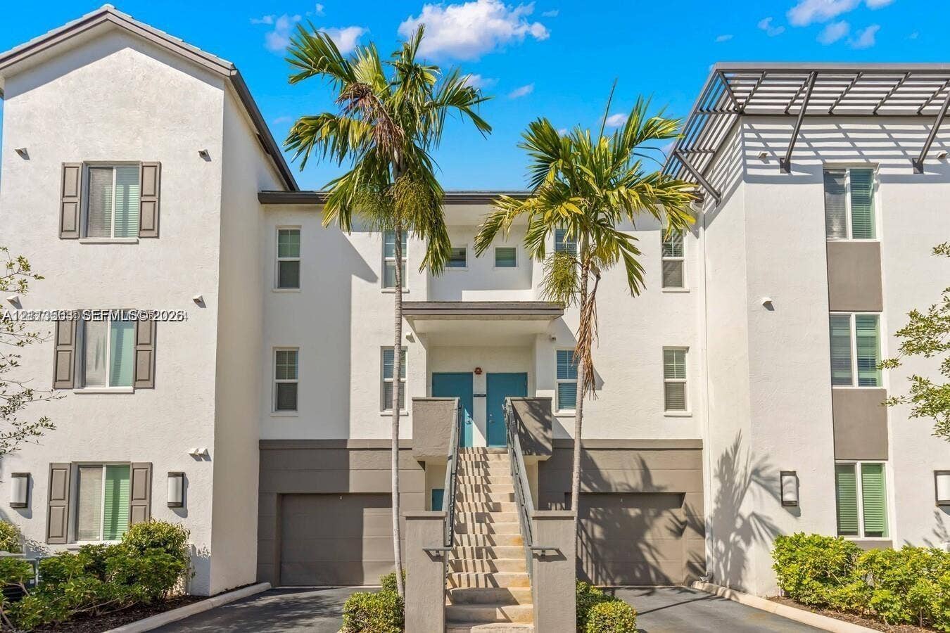 320 Franklin Club Drive, #Boynton, Delray Beach, Delray Beach, FL 33483 Multi-level stucco exterior featuring integrated dual-car garages, a central staircase with decorative railings, and contemporary window shutters