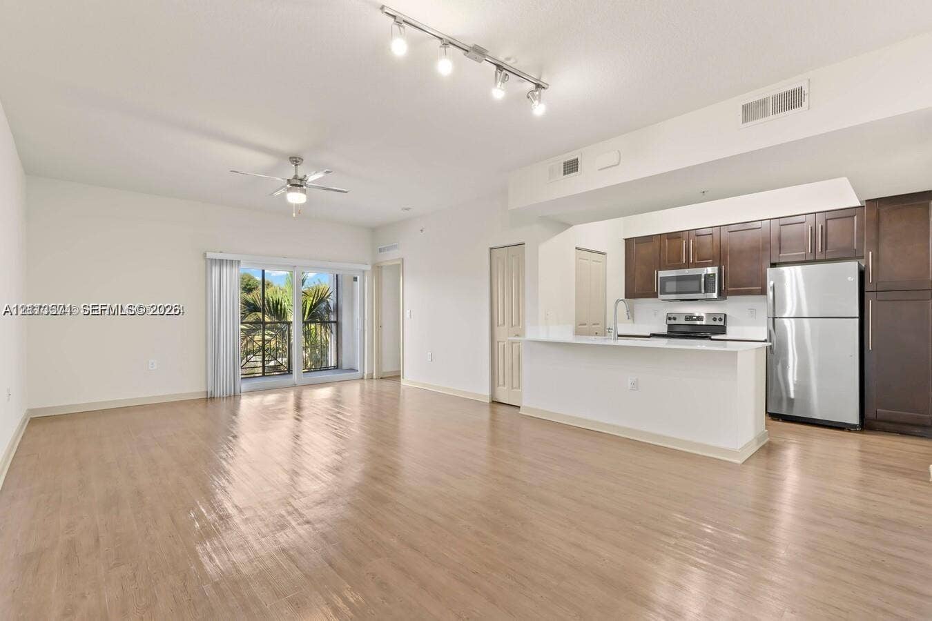 320 Franklin Club Drive, #Lantana, Delray Beach, Delray Beach, FL 33483 Open-concept interior featuring wood-finish flooring, a kitchen with dark cabinetry and stainless steel appliances, a breakfast bar, recessed track lighting, and a sliding glass door