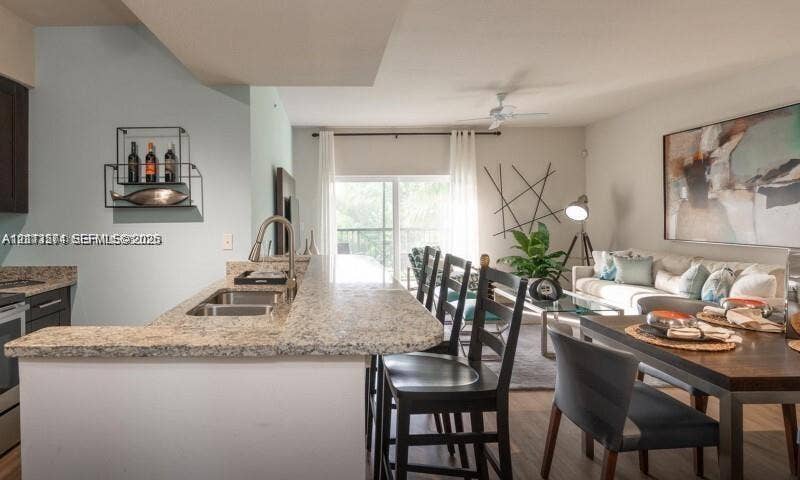 320 Franklin Club Drive, #Lantana, Delray Beach, Delray Beach, FL 33483 Kitchen featuring a breakfast bar, stone-finish countertops, stainless steel dual-basin sink, and dark cabinetry, with wood-finish flooring throughout