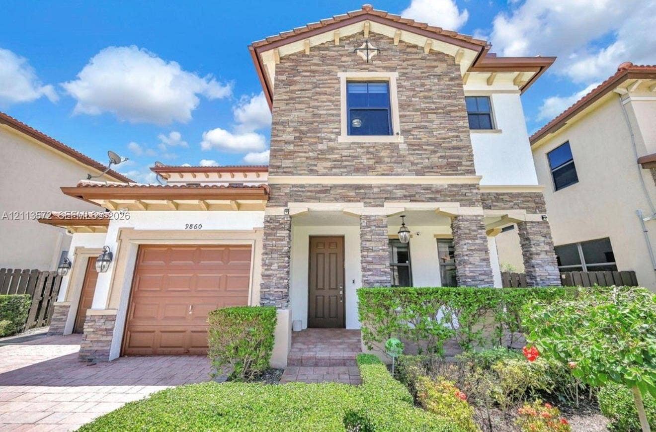 9860 NW 86th Terrace, Doral, FL 33178 Two-story exterior featuring stone veneer accents, a tiled roof, a paved driveway, and an arched entry with recessed lighting