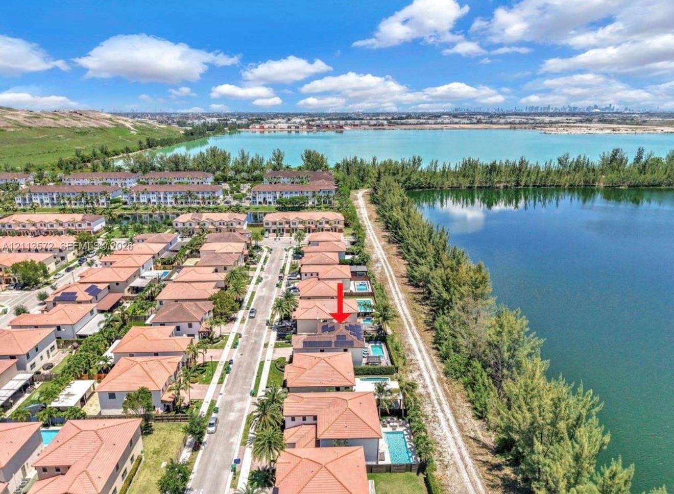 9860 NW 86th Terrace, Doral, FL 33178 Aerial perspective of a multi-story residence featuring a tile roof, solar panel array, and a private rear swimming pool