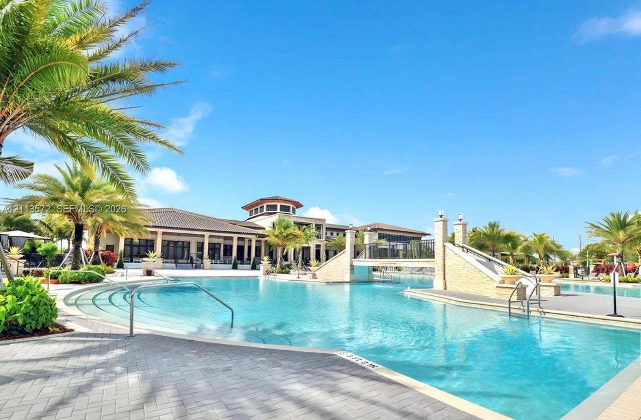 9860 NW 86th Terrace, Doral, FL 33178 Swimming pool with stone-clad bridge, tiered entry steps, metal handrails, and paver decking