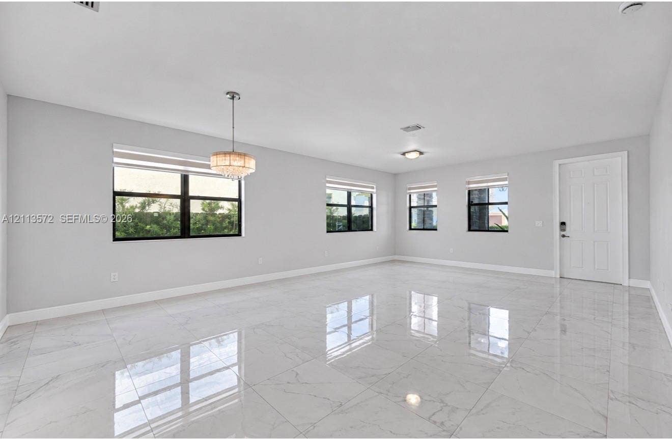 9860 NW 86th Terrace, Doral, FL 33178 Polished stone-finish flooring, multi-pane windows with black frames, and a tiered crystal chandelier