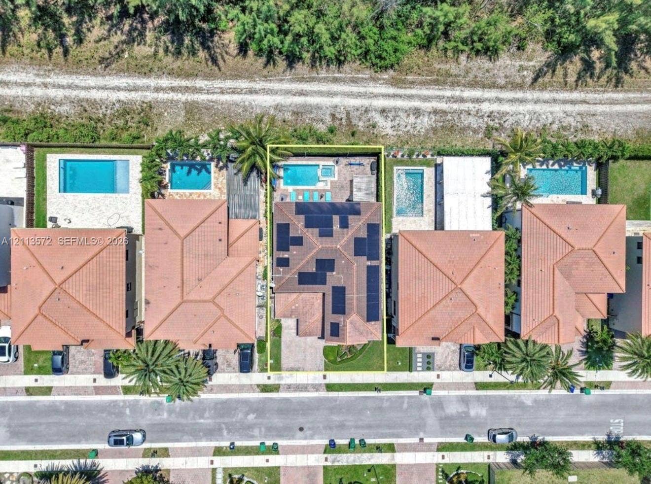 9860 NW 86th Terrace, Doral, FL 33178 Aerial perspective of property featuring a tile roof with integrated solar panels, private swimming pool, spa, and paved rear patio