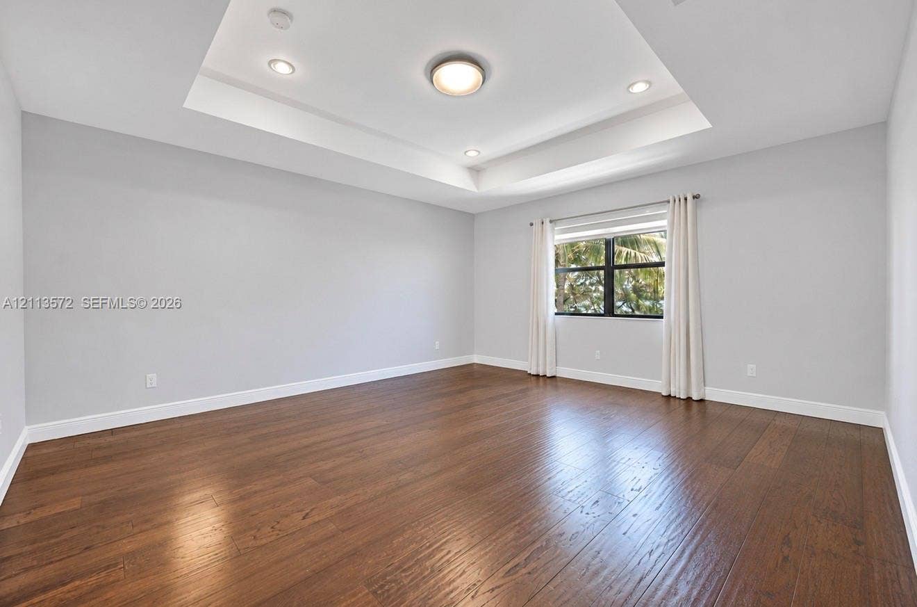 9860 NW 86th Terrace, Doral, FL 33178 Tray ceiling with recessed lighting, wood-finish flooring, and a single-pane window with a dark frame