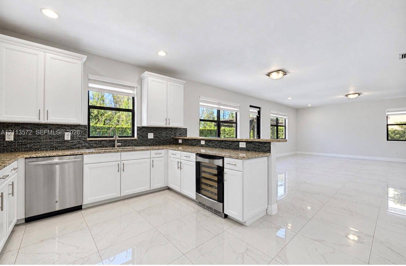 9860 NW 86th Terrace, Doral, FL 33178 Kitchen featuring white shaker-style cabinetry, stone countertops, a dark-toned tile backsplash, stainless steel appliances, and polished tile flooring