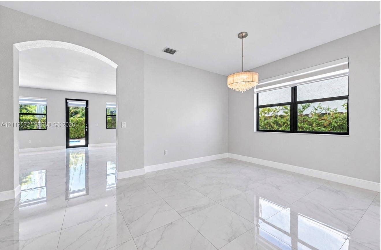 9860 NW 86th Terrace, Doral, FL 33178 Large-format tile flooring with polished finish, arched architectural entry, multi-tiered crystal drum chandelier, and black-framed window casings