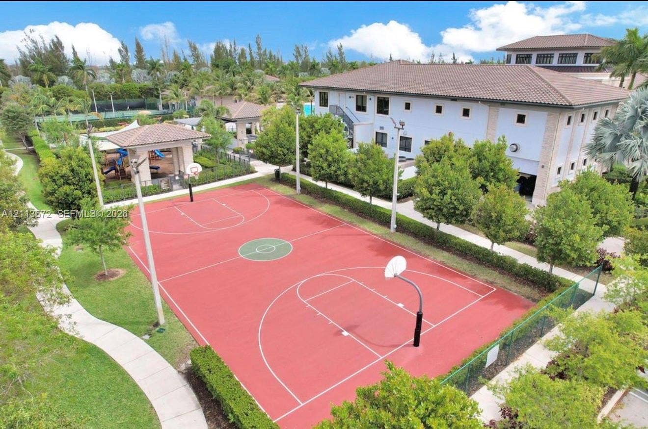9860 NW 86th Terrace, Doral, FL 33178 Full-sized basketball court with a red surface, dual hoops, perimeter fencing, concrete walking paths, and manicured landscaping
