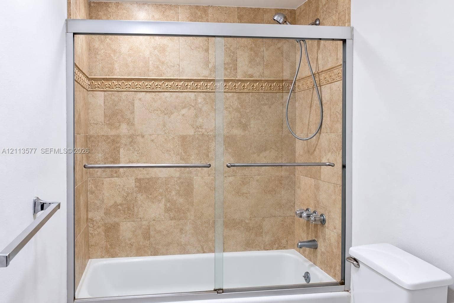 19370 Collins Avenue, #1622, Sunny Isles Beach, FL 33160 Bathtub and shower combination featuring a glass sliding enclosure, floor-to-ceiling tile surround, decorative tile inlay, and chrome finish hardware