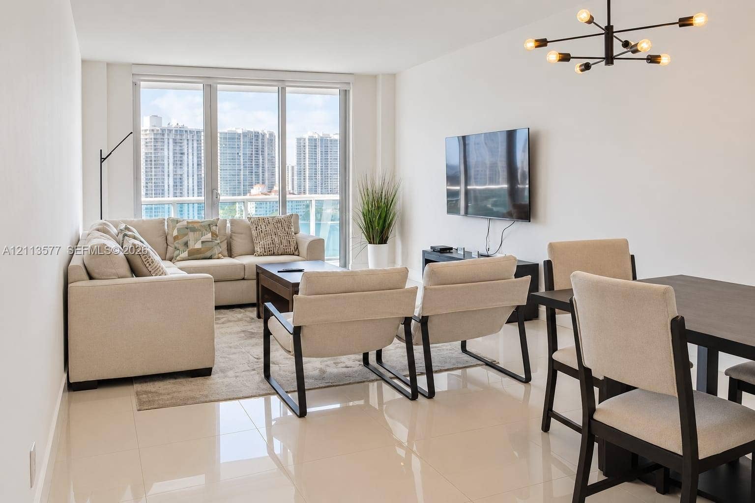 19370 Collins Avenue, #1622, Sunny Isles Beach, FL 33160 Living area featuring large-format tile flooring, floor-to-ceiling windows with a glass balcony railing, and a contemporary multi-arm chandelier