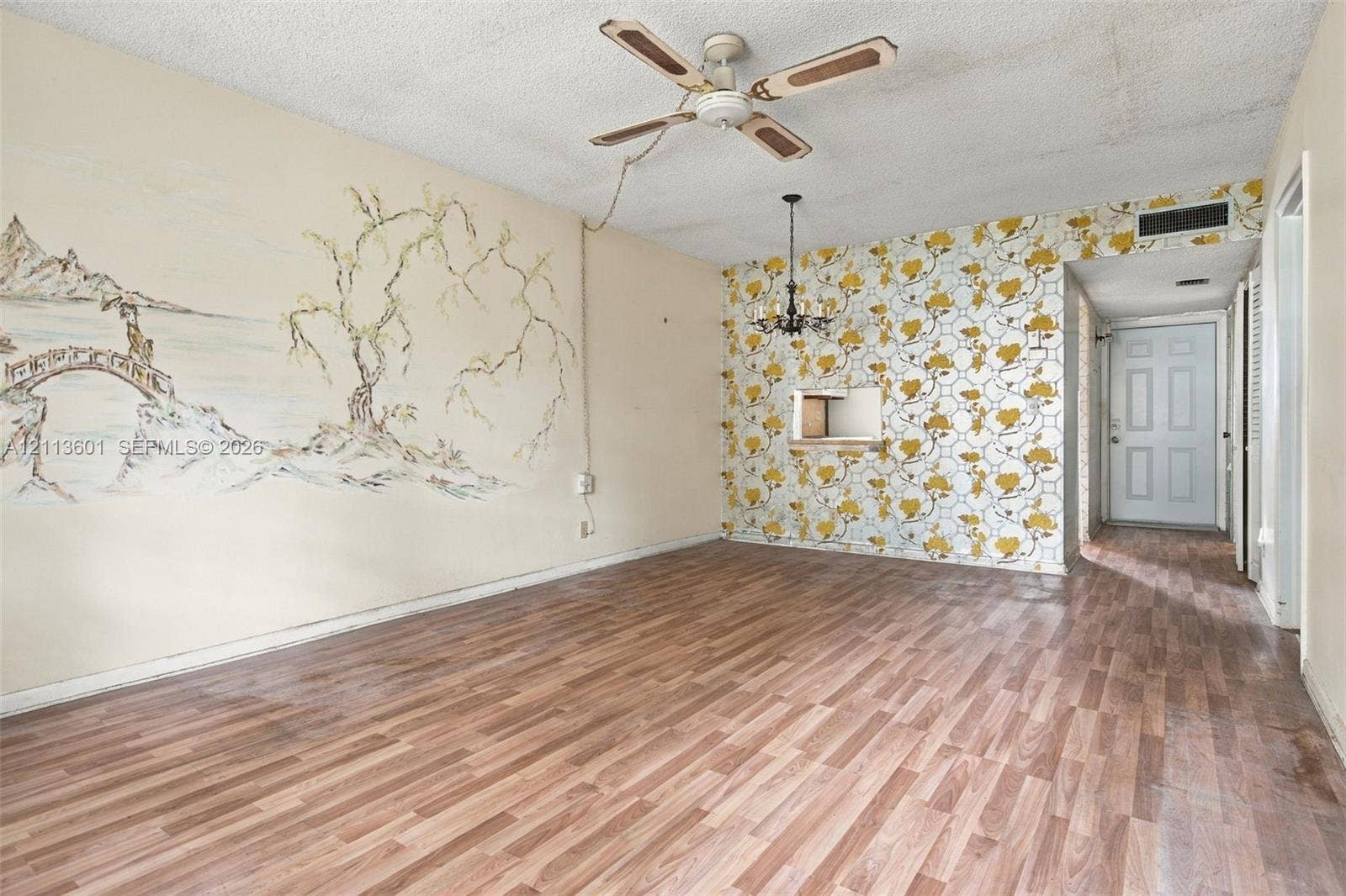 Interior space featuring wood-finish flooring, a multi-arm chandelier, a ceiling fan, and a built-in serving pass-through