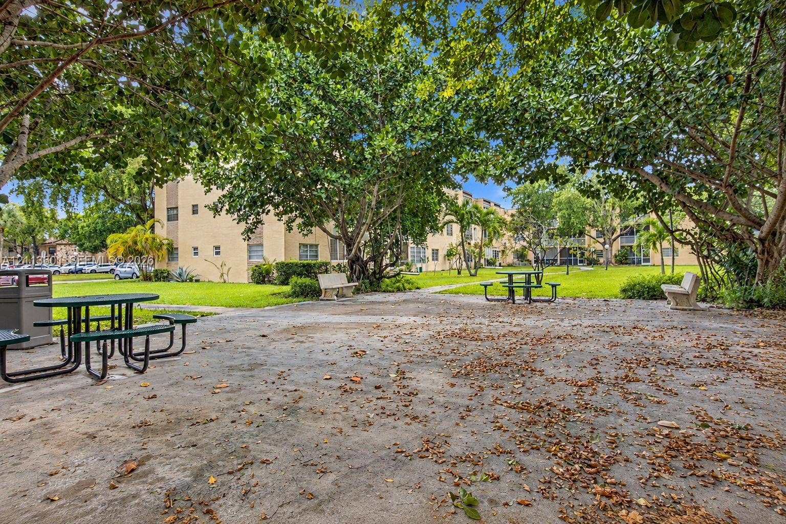 Common area grounds featuring a concrete courtyard, mature shade trees, and built-in stone benches