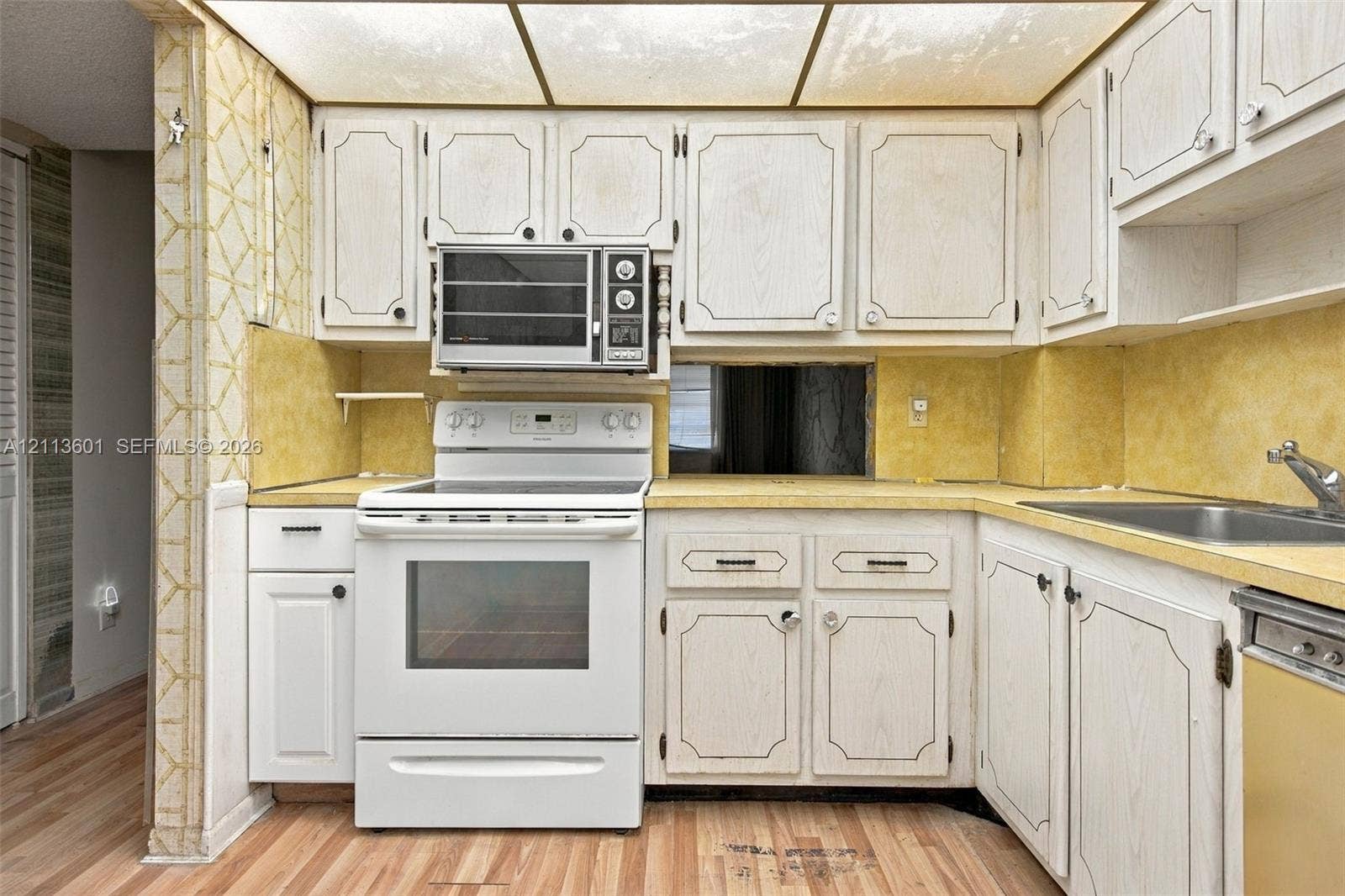 Kitchen featuring wood-finish cabinetry, solid-surface countertops, integrated cooktop and oven range, built-in microwave, and drop-in stainless steel sink