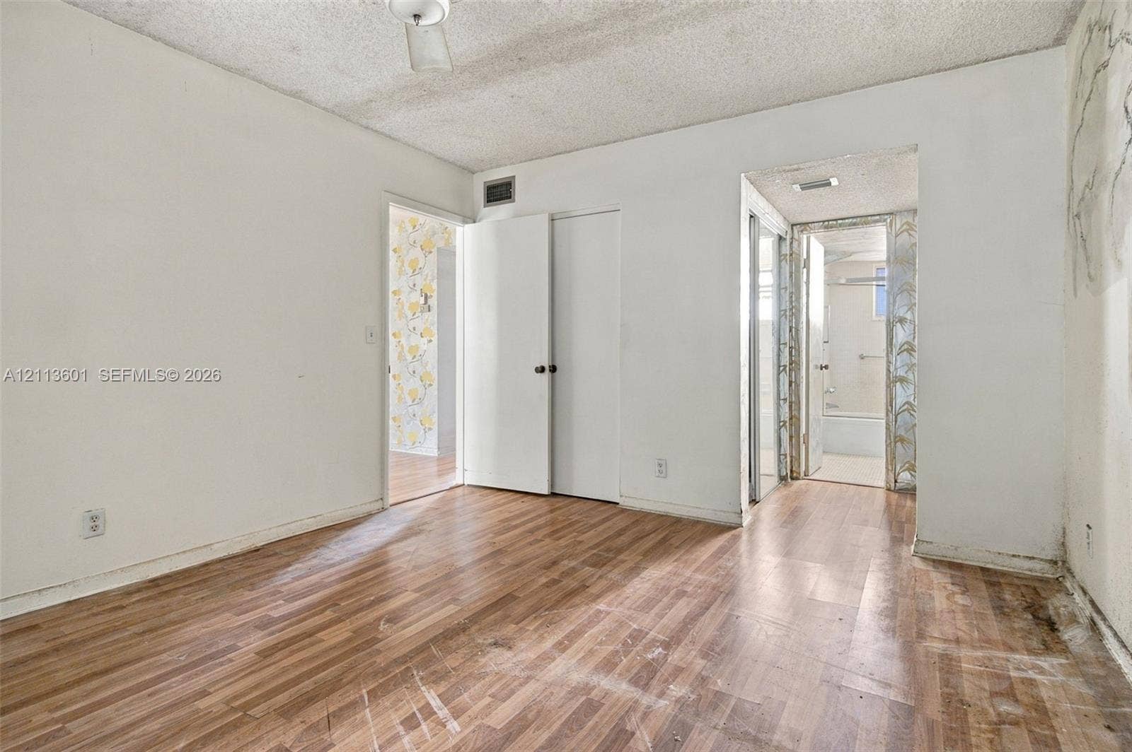 Room featuring wood-finish flooring, white walls, and dual-door closet storage