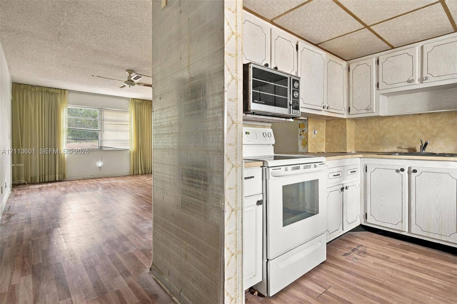 Kitchen featuring white paneled cabinetry, a built-in microwave, a white freestanding range, and wood-finish flooring