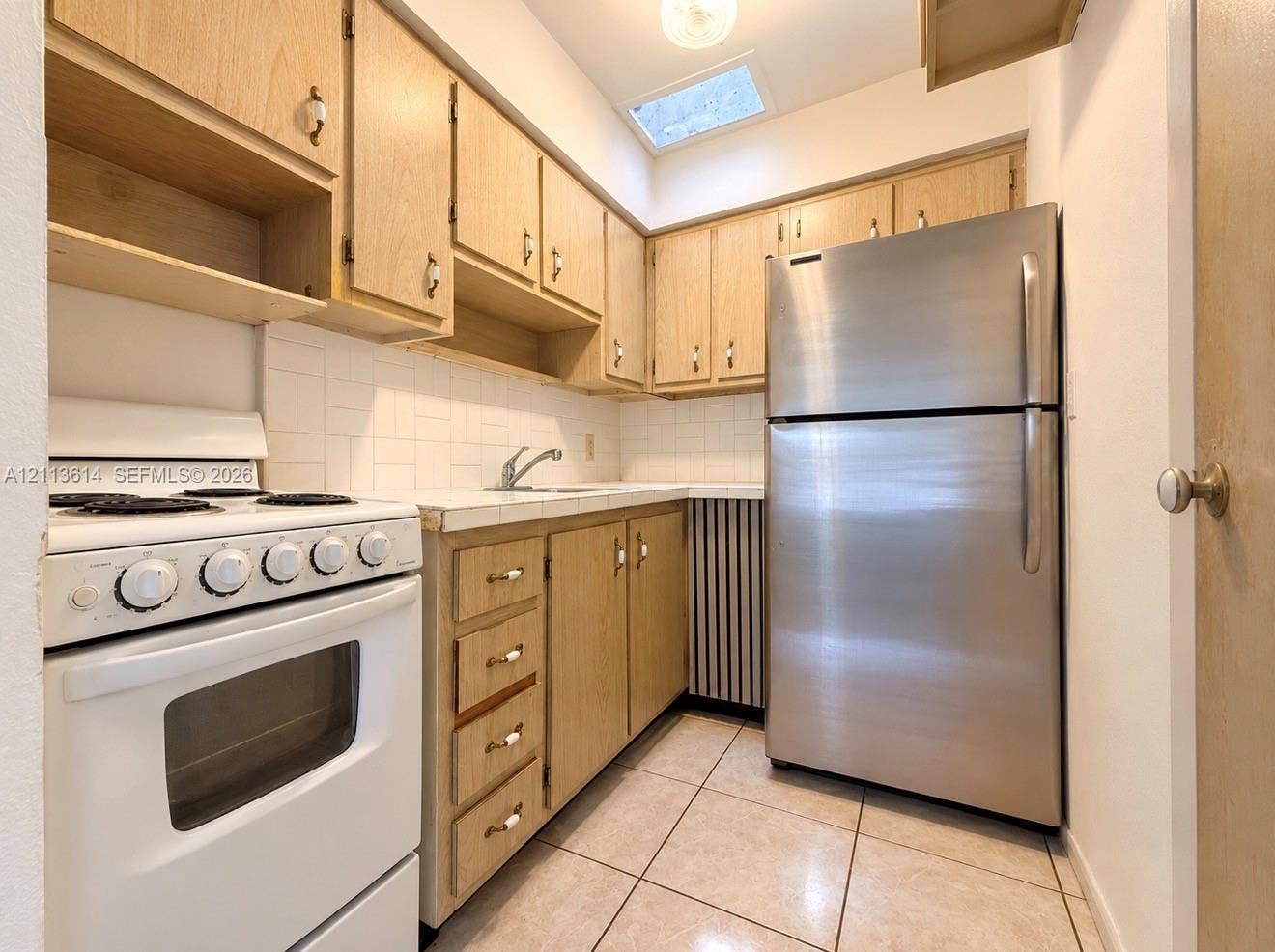 2901 Polk Street, #16, Hollywood, Hollywood, FL 33020 Kitchen featuring wood-finish cabinetry, tile countertops, stainless steel refrigerator, white freestanding range, and ceramic tile flooring