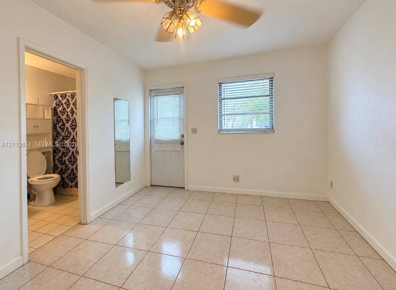 2901 Polk Street, #16, Hollywood, Hollywood, FL 33020 Interior space featuring light-colored tile flooring, a ceiling fan with integrated lighting, a flush-mounted wall mirror, and an exterior door with a window insert
