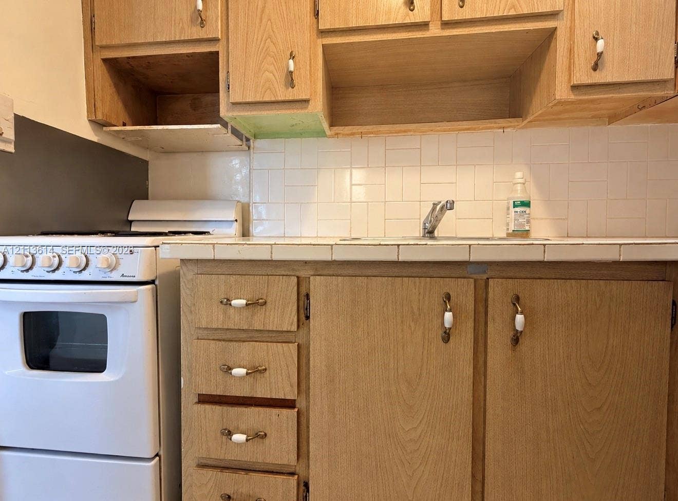 2901 Polk Street, #16, Hollywood, Hollywood, FL 33020 Kitchen area featuring wood-finish cabinetry, tile backsplash, tile countertop, integrated sink with faucet, and built-in gas range