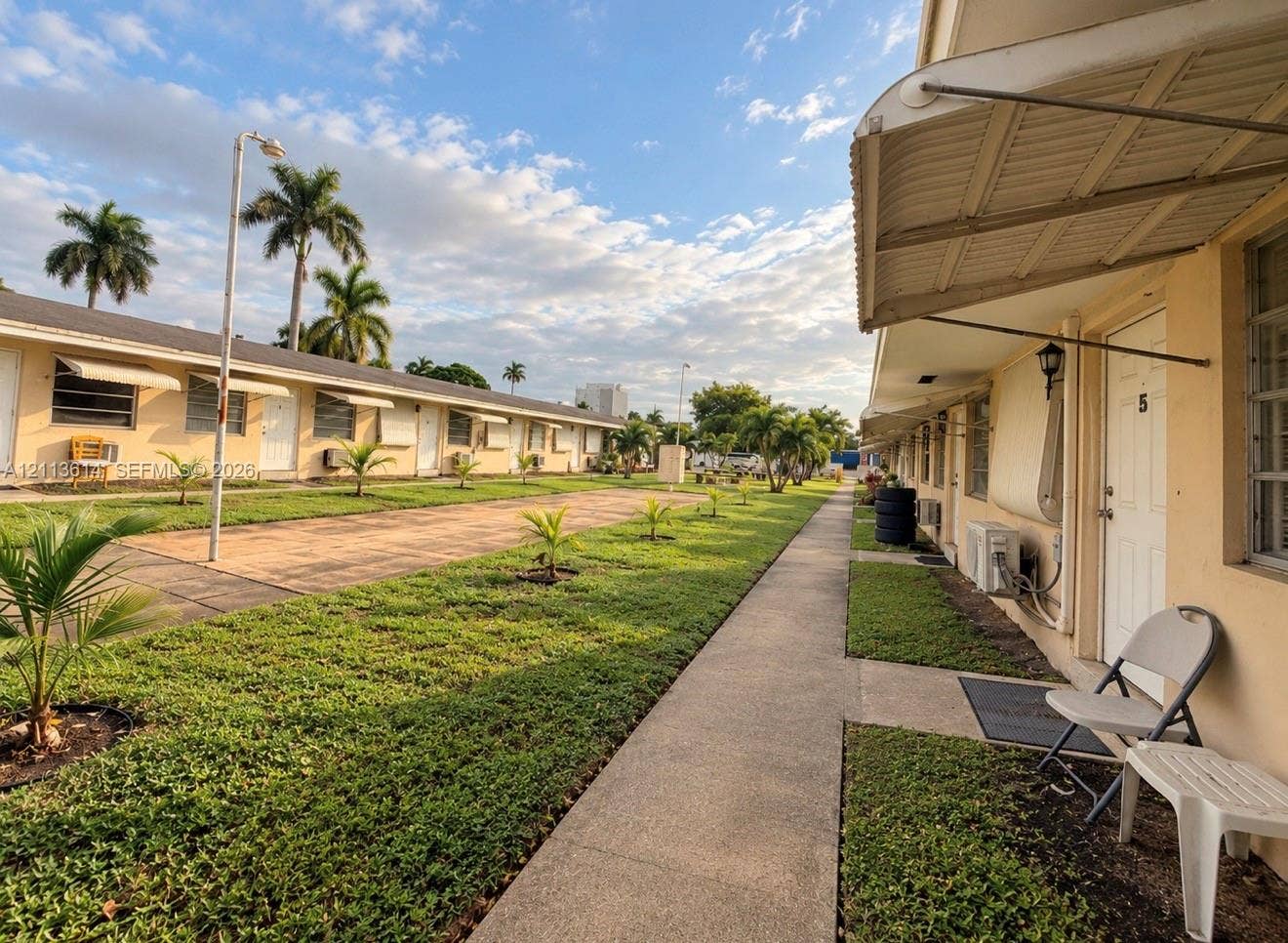2901 Polk Street, #16, Hollywood, Hollywood, FL 33020 Single-story exterior featuring metal awnings, stucco siding, concrete walkways, and manicured landscaping with palms