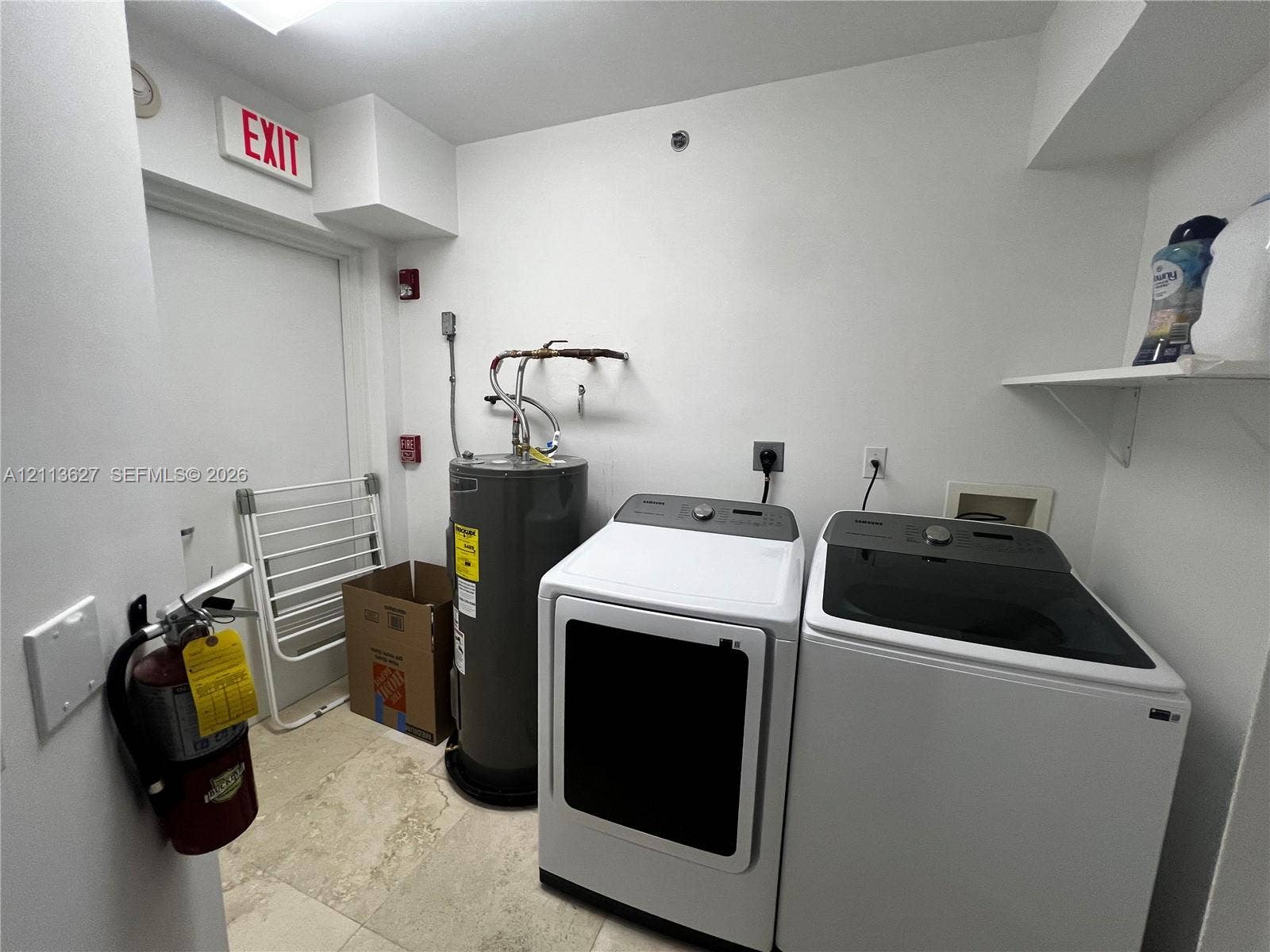 Utility room featuring stone-tile flooring and built-in shelving