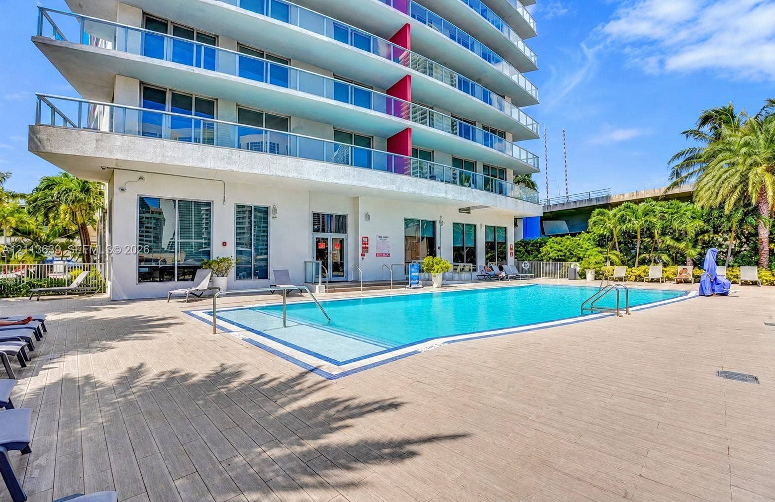 Outdoor swimming pool featuring a tile-accented perimeter, concrete deck surfacing, and tiered architectural balconies above