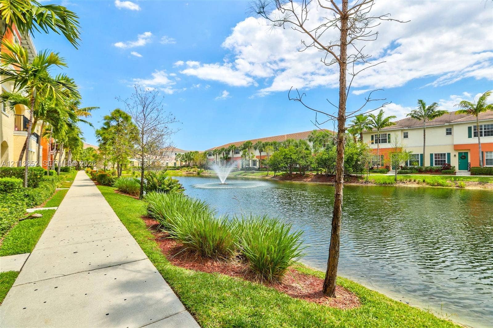 618 SW 1st Lane, Pompano Beach, FL 33060 Community grounds featuring a central pond, a fountain, a paved walking path, mature palm trees, and manicured landscaping
