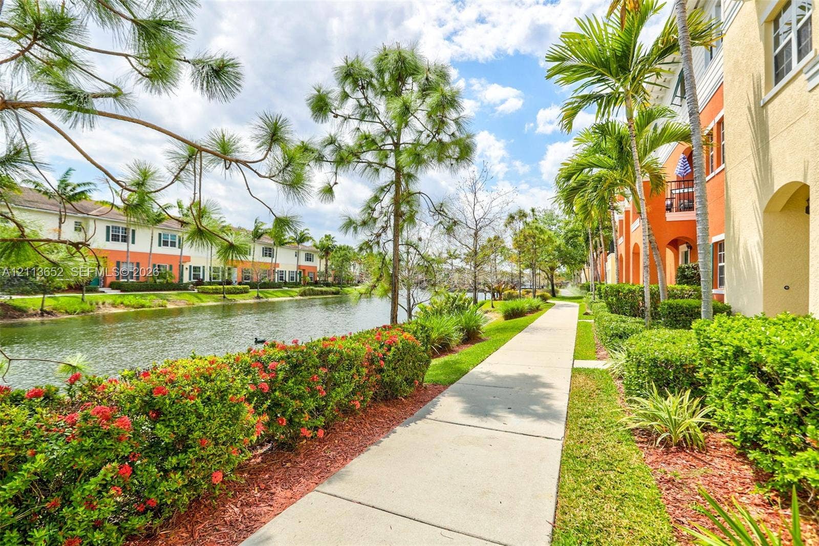 618 SW 1st Lane, Pompano Beach, FL 33060 Concrete walkway lined with manicured hedges, mature palm trees, and native landscaping along a waterway