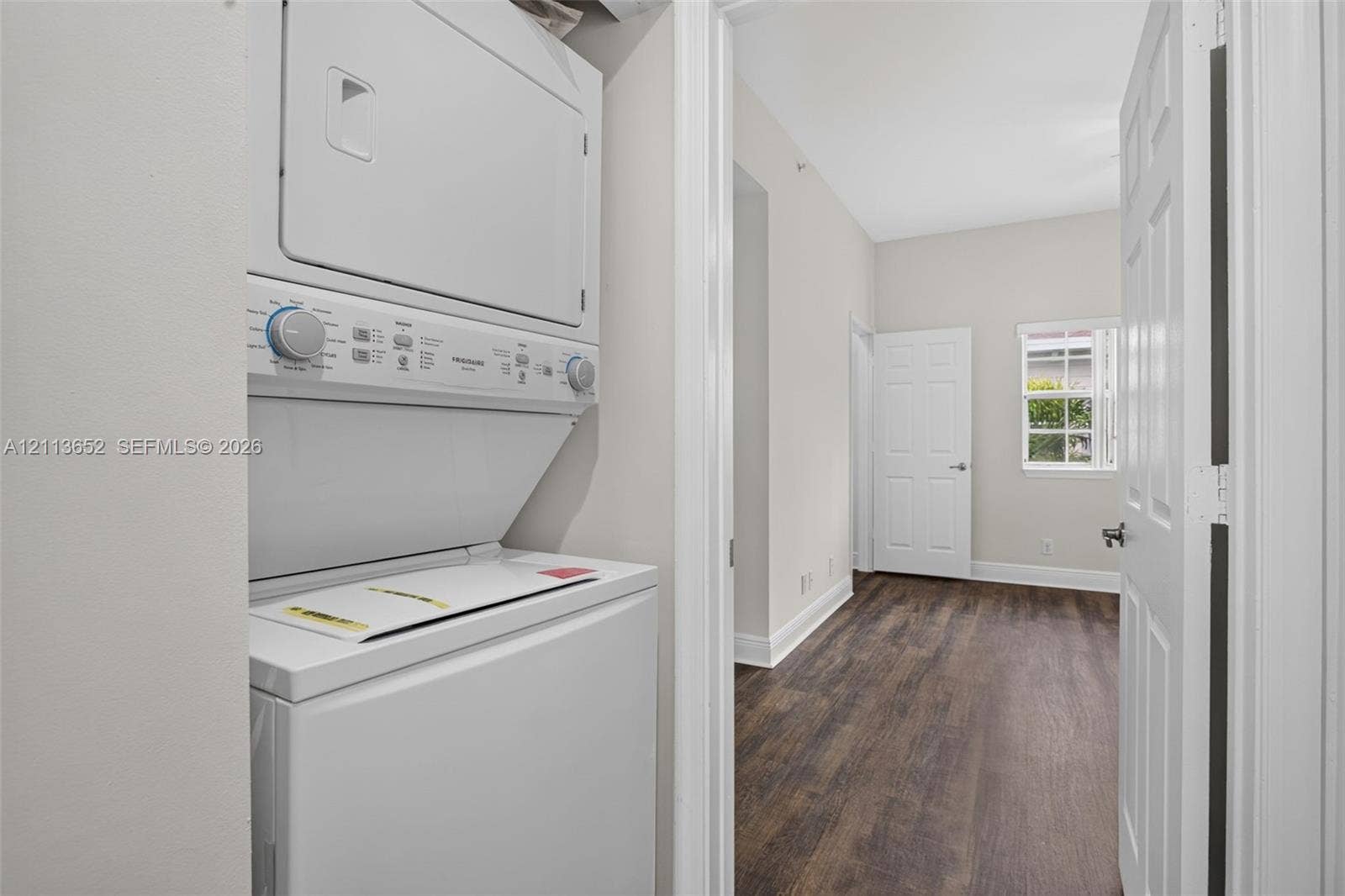 618 SW 1st Lane, Pompano Beach, FL 33060 Stacked laundry appliance, wood-finish flooring, white panel doors, and a single-pane window