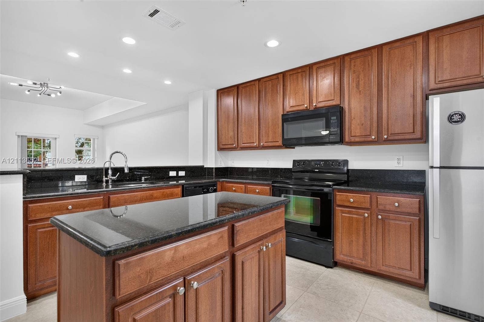 618 SW 1st Lane, Pompano Beach, FL 33060 Kitchen featuring dark stone countertops, natural wood-finish cabinetry, center island, stainless steel refrigerator, and recessed lighting