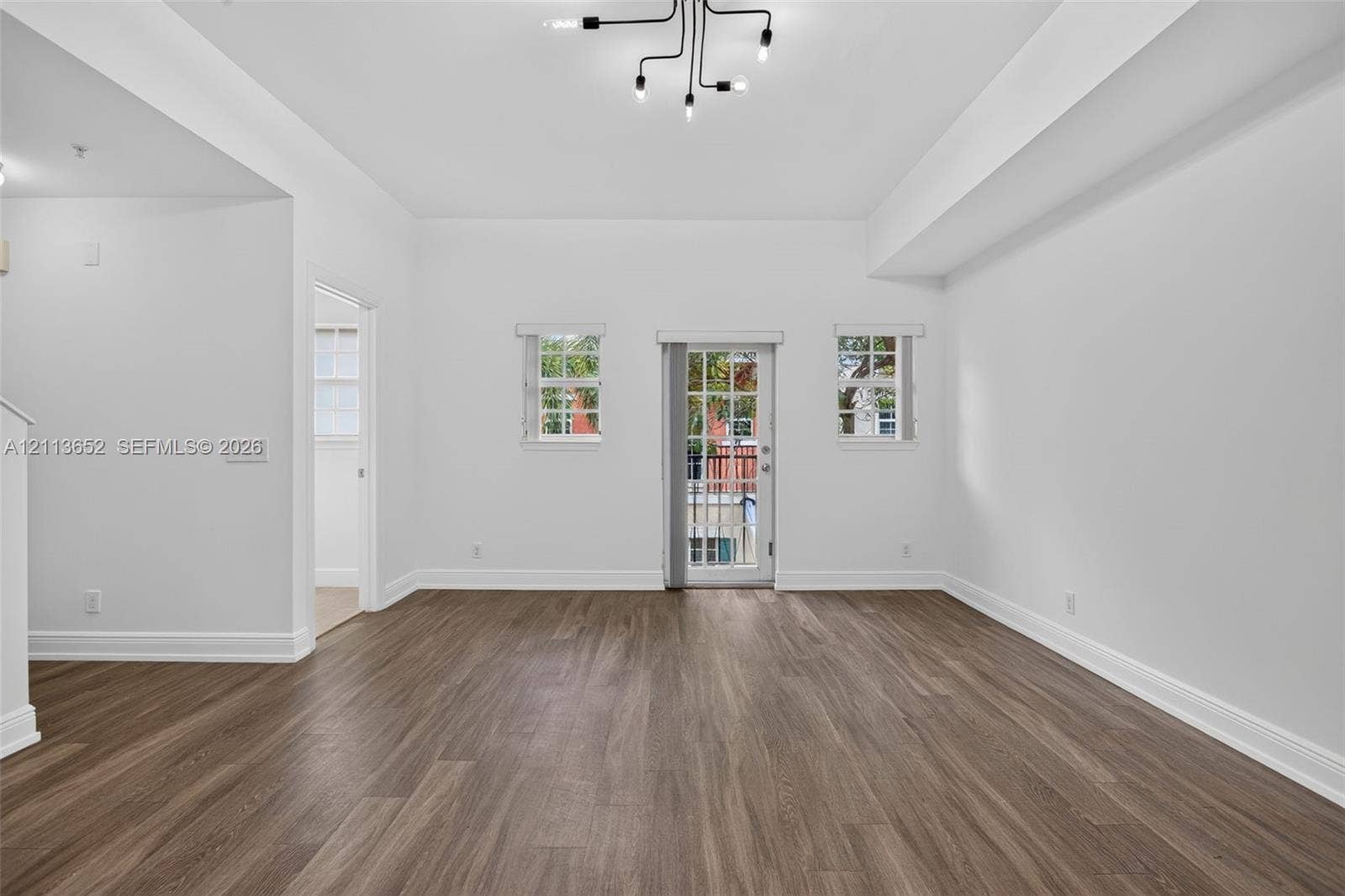 618 SW 1st Lane, Pompano Beach, FL 33060 Interior space featuring high ceilings, wood-finish flooring, a multi-light modern chandelier, and a glass-paneled exterior door flanked by windows