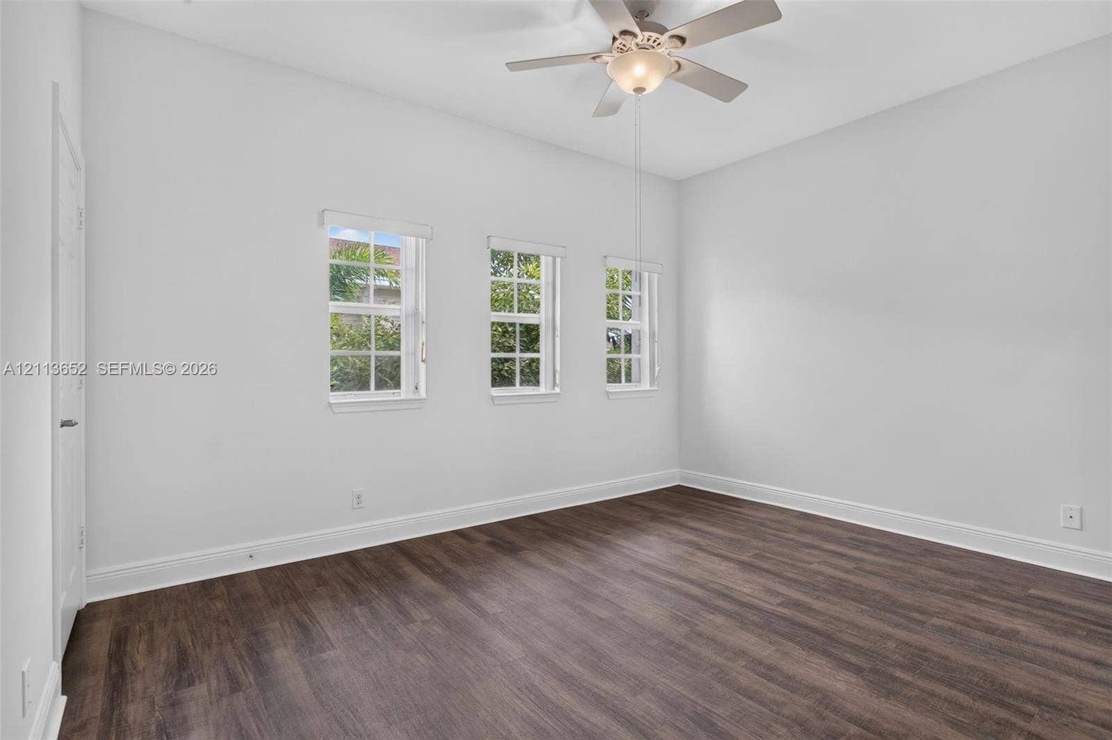 618 SW 1st Lane, Pompano Beach, FL 33060 Room featuring wood-finish flooring, high ceilings, three multi-pane windows, and a central ceiling fan with an integrated light fixture