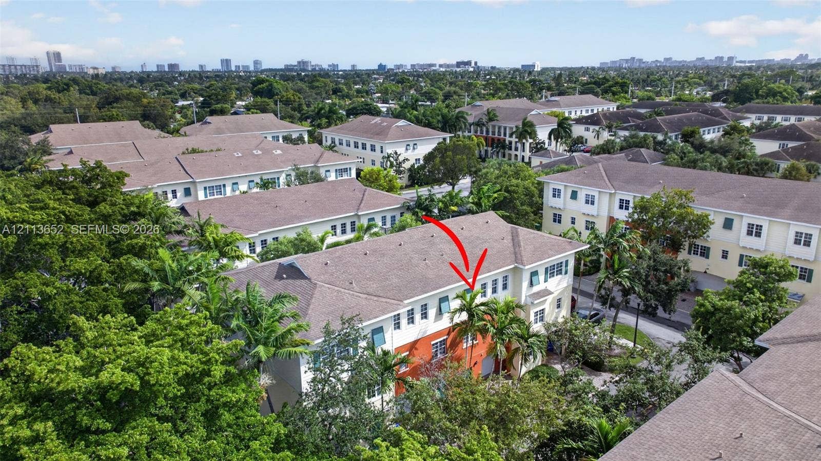 618 SW 1st Lane, Pompano Beach, FL 33060 Multi-level townhouse featuring a shingled roof, stucco exterior with vibrant accents, decorative window shutters, and established perimeter landscaping