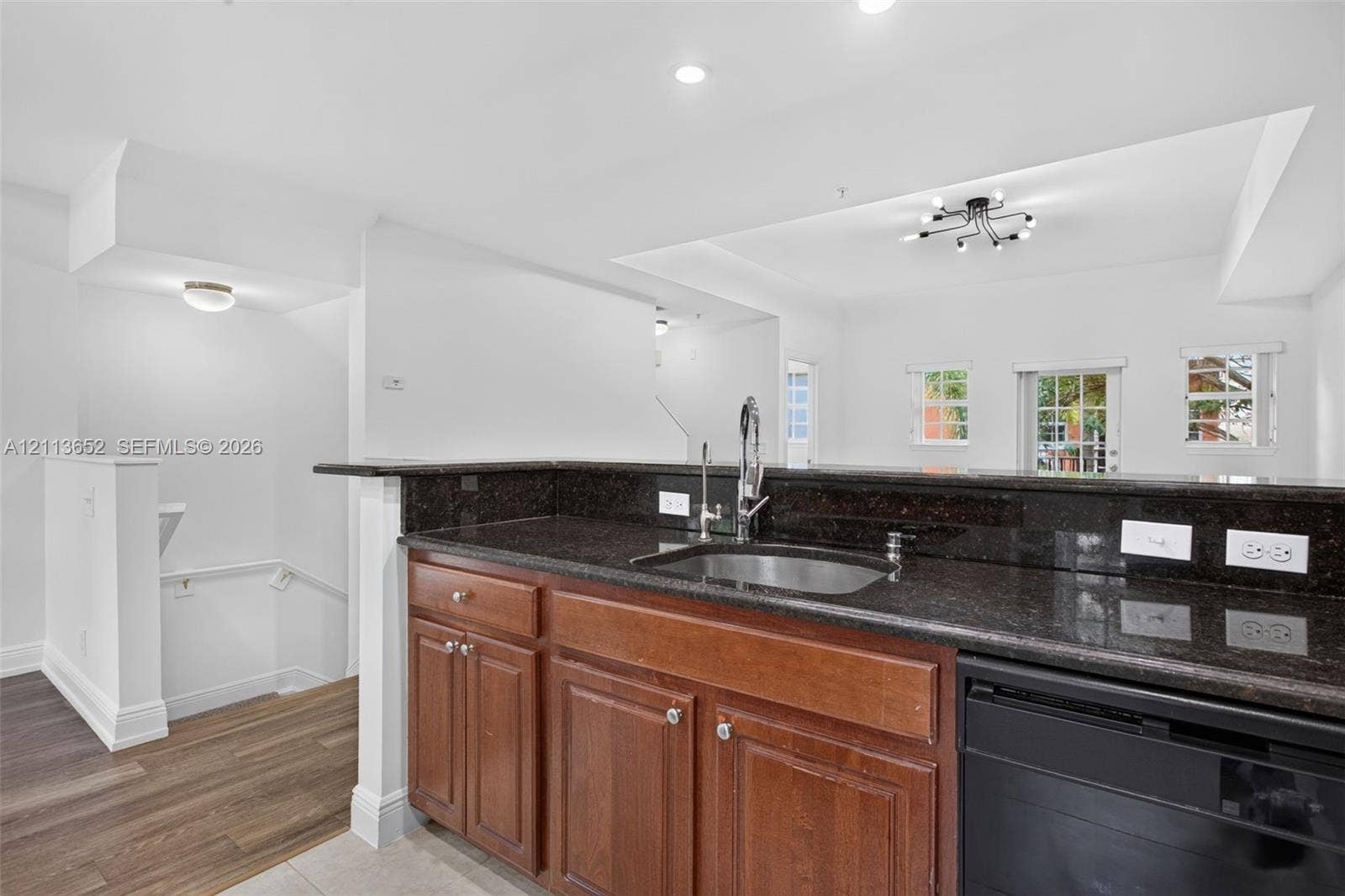 618 SW 1st Lane, Pompano Beach, FL 33060 Kitchen featuring dark stone countertops, wood-finish cabinetry, stainless steel sink with high-arc faucet, integrated dishwasher, and wood-finish flooring