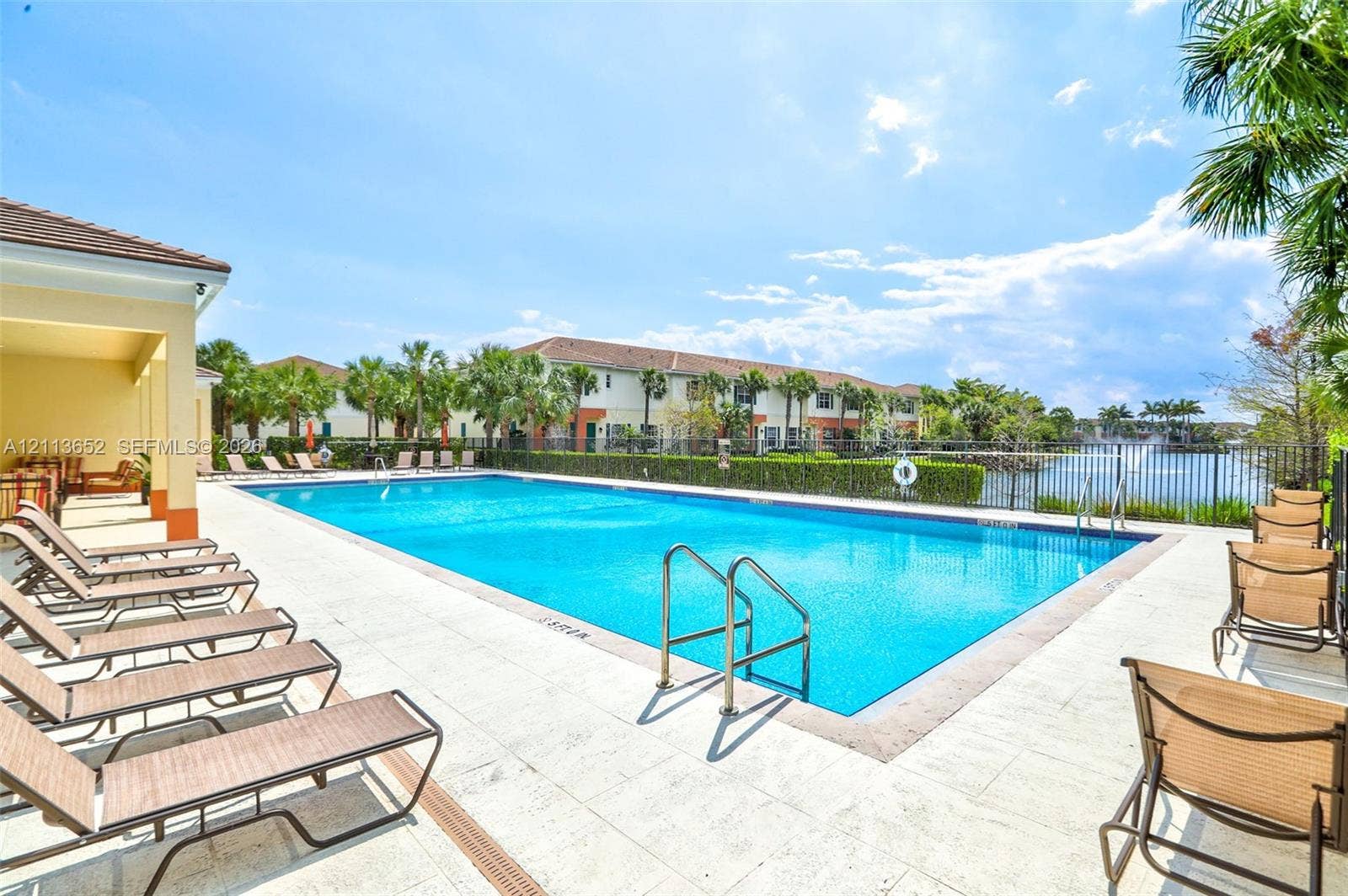 618 SW 1st Lane, Pompano Beach, FL 33060 Rectangular outdoor swimming pool featuring a light-colored paver deck, metal perimeter fencing, and stainless-steel ladders