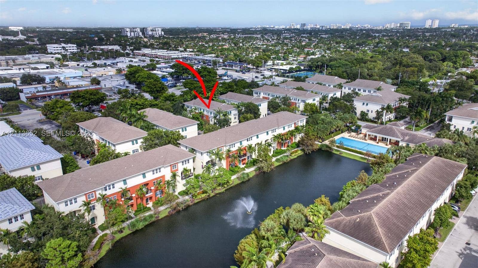 618 SW 1st Lane, Pompano Beach, FL 33060 Aerial perspective of residential community featuring a water feature with fountain, mature landscaping, and common-area swimming pool