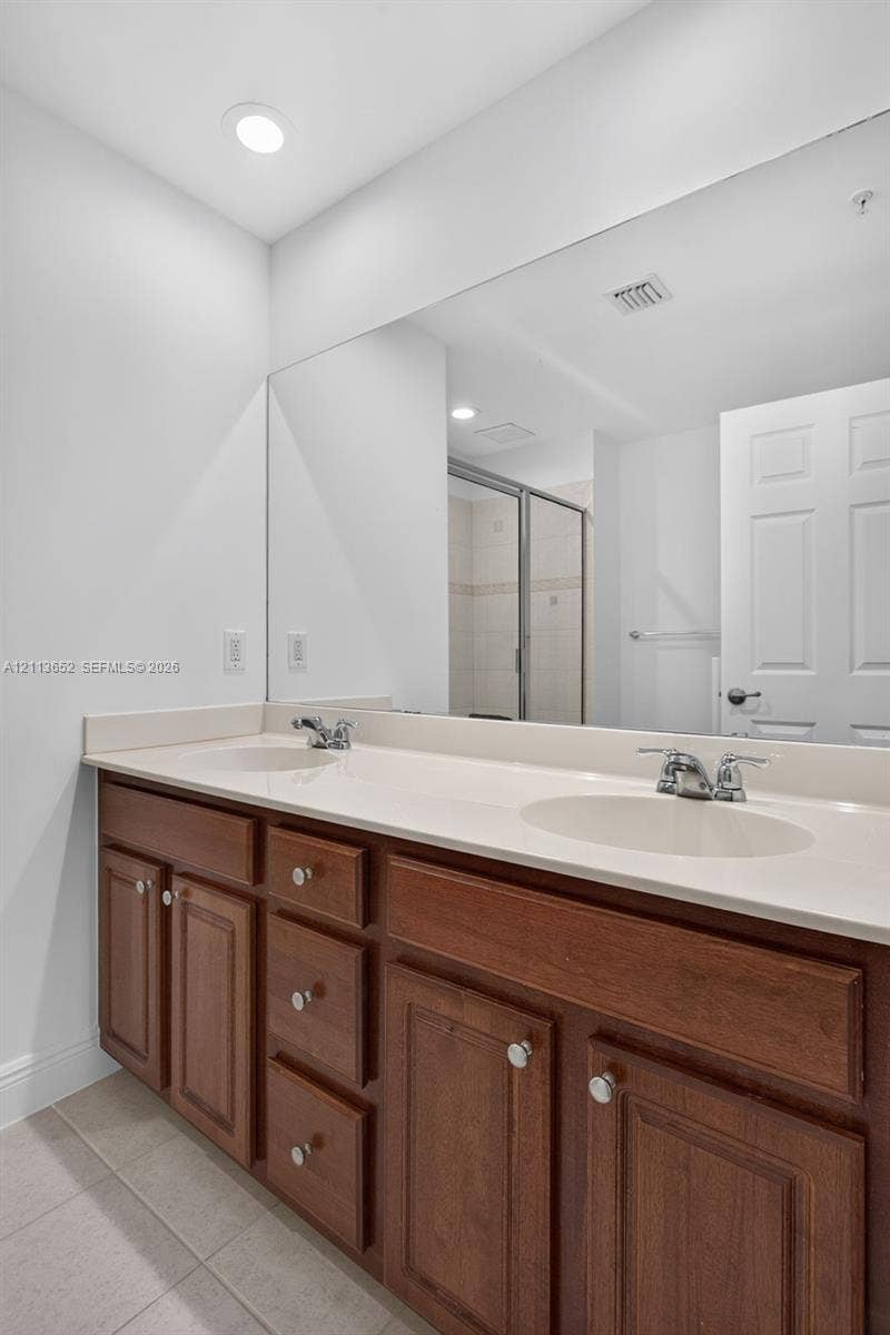 618 SW 1st Lane, Pompano Beach, FL 33060 Dual-sink vanity with wood-finish cabinetry, solid-surface countertop, recessed lighting, and a large-format mirror